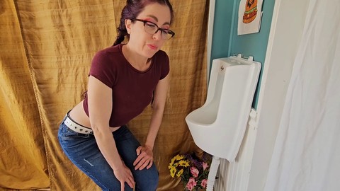 Eine nerdige Fee zeigt ihr Stehpinkeln in einer öffentlichen Toilette